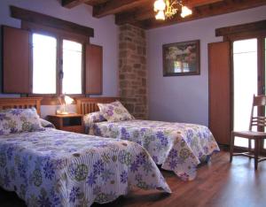 a bedroom with two beds and a chair and windows at Casa Rural Enarakabi in Zunzarren