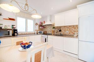 a kitchen with white cabinets and a bowl of fruit on a table at Sunbathing with private swimming pool in Calpe