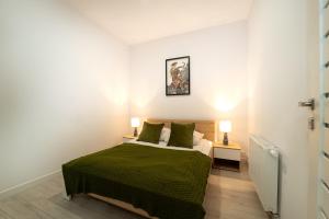 1 dormitorio con 1 cama con sábanas verdes y 2 lámparas en Reymonta 22 Apartamenty, en Opole