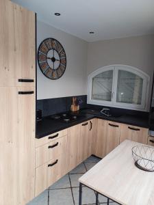 eine Küche mit einer Uhr an der Wand und einem Tisch in der Unterkunft Studio bord de mer in Port-la-Nouvelle