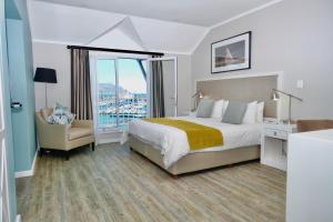 een slaapkamer met een bed, een stoel en een raam bij Simon's Town Quayside Hotel in Simonʼs Town +72 foto's