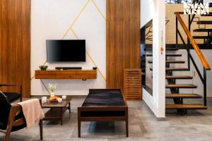 sala de estar con TV y escalera en StayVista's One Villa - Pet-friendly charm with Farm views, Modern decor & A refreshing plunge pool, en Karjat