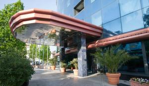 a building with a red awning and potted plants at Hotel Alexander Business and Conference in Abano Terme