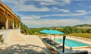 a swimming pool with chairs and a blue umbrella at Entre 2 Mers - Charming guesthouse in Cancon