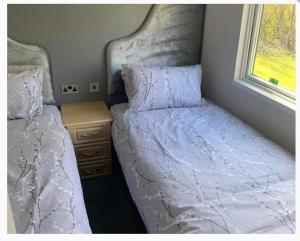 a bedroom with two beds and a window at Lodge Retreat 4 - Haggerston Castle in Berwick-Upon-Tweed +4 photos