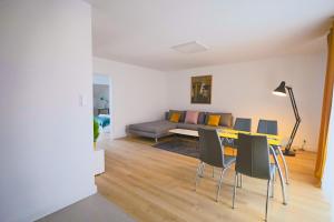Una sala de estar con un sofá, una mesa y sillas. en Reymonta 22 Apartamenty, en Opole