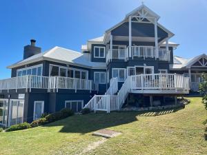 a large blue house with white railings on a lawn at SandDollar - Entire house in Cape St Francis