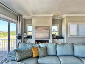 a blue couch in a living room with a kitchen at SandDollar - Entire house in Cape St Francis