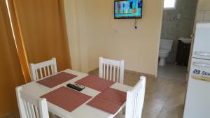 una mesa blanca con sillas y TV en la cocina en Apartamentos Los Teros en San José