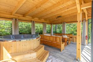 a wooden cabin with a hot tub and a table at Kaszubska Kryjówka - Komfortowy 8 osobowy Domek w sercu Kaszub - Jacuzzi, Sauna, Rowerek Wodny, Jezioro, Las, Salon Gier! in Sulęczyno