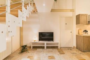 a living room with a television and a staircase at Sassi Suite - Elegant Historic Home in Matera