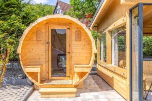 a wooden sauna with an arched door on a house at Kaszubska Kryjówka - Komfortowy 8 osobowy Domek w sercu Kaszub - Jacuzzi, Sauna, Rowerek Wodny, Jezioro, Las, Salon Gier! in Sulęczyno