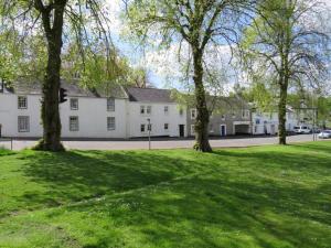 a large white building with trees in the grass at Fifty Five on Gilmour Street in Eaglesham