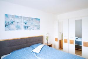 a bedroom with a blue bed and a painting on the wall at Ferienhaus Nr 4, Kategorie Premium L, Feriendorf Hochbergle, Allgäu in Lechbruck