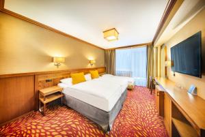una camera d'albergo con un letto e una TV a schermo piatto di Harmony Hotel a Špindlerův Mlýn