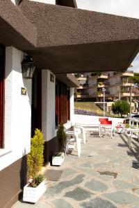 a patio with white chairs and potted plants on a building at Hotel Acuarium in Villa Gesell