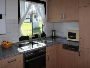 a kitchen with a sink and a microwave and a window at Ferienhaus Nr 5, Kategorie Komfort, Feriendorf Hochbergle, Allgäu in Lechbruck