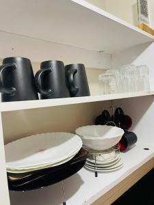 a white shelf with plates and bowls on it at A modern affordable stylish bedsitter centrally located in nairobi in Nairobi