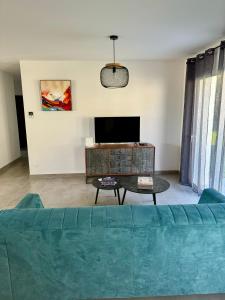 a living room with a blue couch and a tv at Maison du Cos, neuve avec 3 chambres et un garage in Lamothe-Capdeville