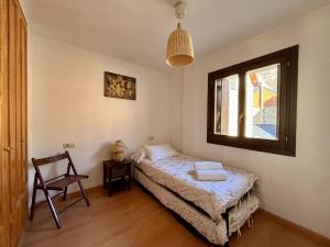 a bedroom with a bed and a window and a chair at BPirineos-Casa Chuanina in Benasque