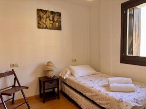 a bedroom with a bed and a chair and a window at BPirineos-Casa Chuanina in Benasque