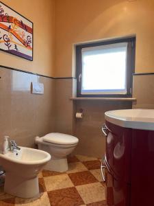 a bathroom with a toilet and a sink and a window at Sweet Home Apartment in Cavaion Veronese