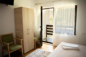 ein Zimmer mit einem Bett und einem Stuhl und einem Fenster in der Unterkunft Casa Valea Prejbei in Rau Sadului