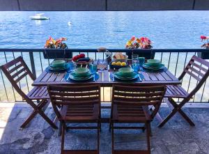 a wooden table with chairs and food on a balcony at Pied dans l’Eau in Brezzo