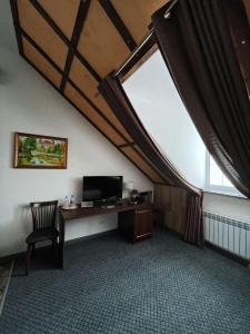 an attic room with a desk and a large window at Edelhof in Karagandy