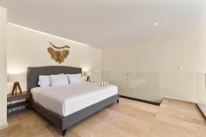 a bedroom with a large bed with white sheets at Loft Hermosa at Tulum's Mistiq Temple II Beaches in Tulum