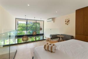 a bedroom with a bed and a glass wall at Loft Hermosa at Tulum's Mistiq Temple II Beaches in Tulum