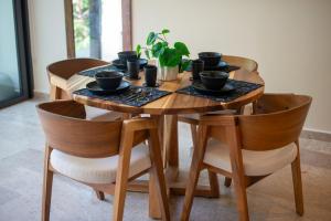 a wooden table with four chairs and a table with cups at Loft Hermosa at Tulum's Mistiq Temple II Beaches in Tulum