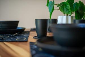 a wooden table with black cups and a potted plant at Loft Hermosa at Tulum's Mistiq Temple II Beaches in Tulum