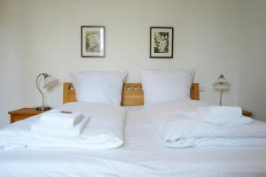 un letto bianco con lenzuola e cuscini bianchi di Wohnensemble mit 3 separaten Bereichen- 2 Küchen- 3 Badezimmer- 10 Personen- Garten- Parkplatz a Wolfsburg