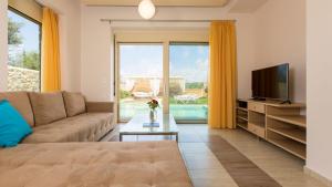 a living room with a couch and a television at Blue Mare Villa Rethimno in Magnisía