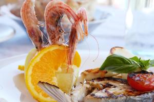 a plate of food with shrimp and an orange slice at Hotel La Certosa in Massa Lubrense