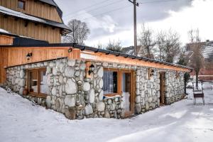 a stone house in the snow in front of a building at Apartament Hanka z Jacuzzi i widokiem na góry in Zakopane