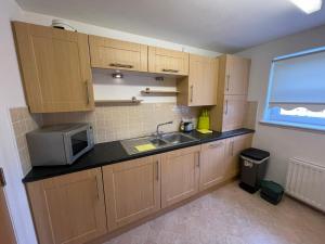 een kleine keuken met een spoelbak en een magnetron bij Workers 3 bedroom beach boulevard apt in Aberdeen