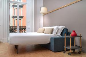 a bedroom with a white bed and a blue couch at Hotel Piazza Bellini & Apartments in Naples