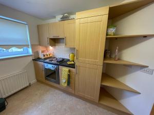 een kleine keuken met houten kasten en een fornuis bij Workers 3 bedroom beach boulevard apt in Aberdeen +3 foto's