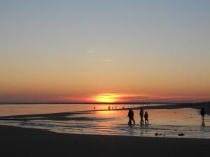 a group of people walking on the beach at sunset at Apartamento acogedor El portil in El Portil