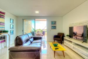 a living room with a leather couch and a table at Breezes do cumbuco in Caucaia