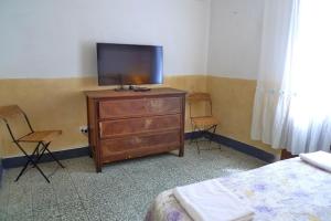 a bedroom with a tv on a dresser with two chairs at Casa Vista Mare in Bosa
