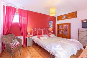 una camera da letto con un letto e una parete rossa di Casa del Tio Primitivo a Navarredonda de Gredos