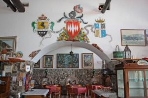 a dining room with red tables and a crest on the wall at Hotel La Certosa in Massa Lubrense