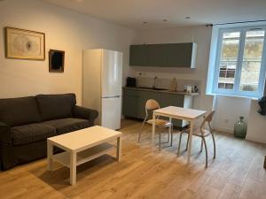 a living room with a couch and a table and a refrigerator at Studio climatisé in Trévoux