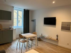 a living room with a table and chairs and a kitchen at Studio climatisé in Trévoux