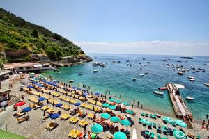 a beach with many umbrellas and boats in the water at Hotel La Certosa in Massa Lubrense