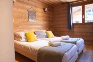 Dos camas en una habitación con paredes de madera. en Apartment Morzine Central - Mountain Voyages, en Morzine