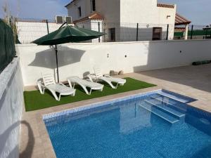 a swimming pool with lounge chairs and an umbrella and a pool at House Lago Azul in Cuevas del Almanzora